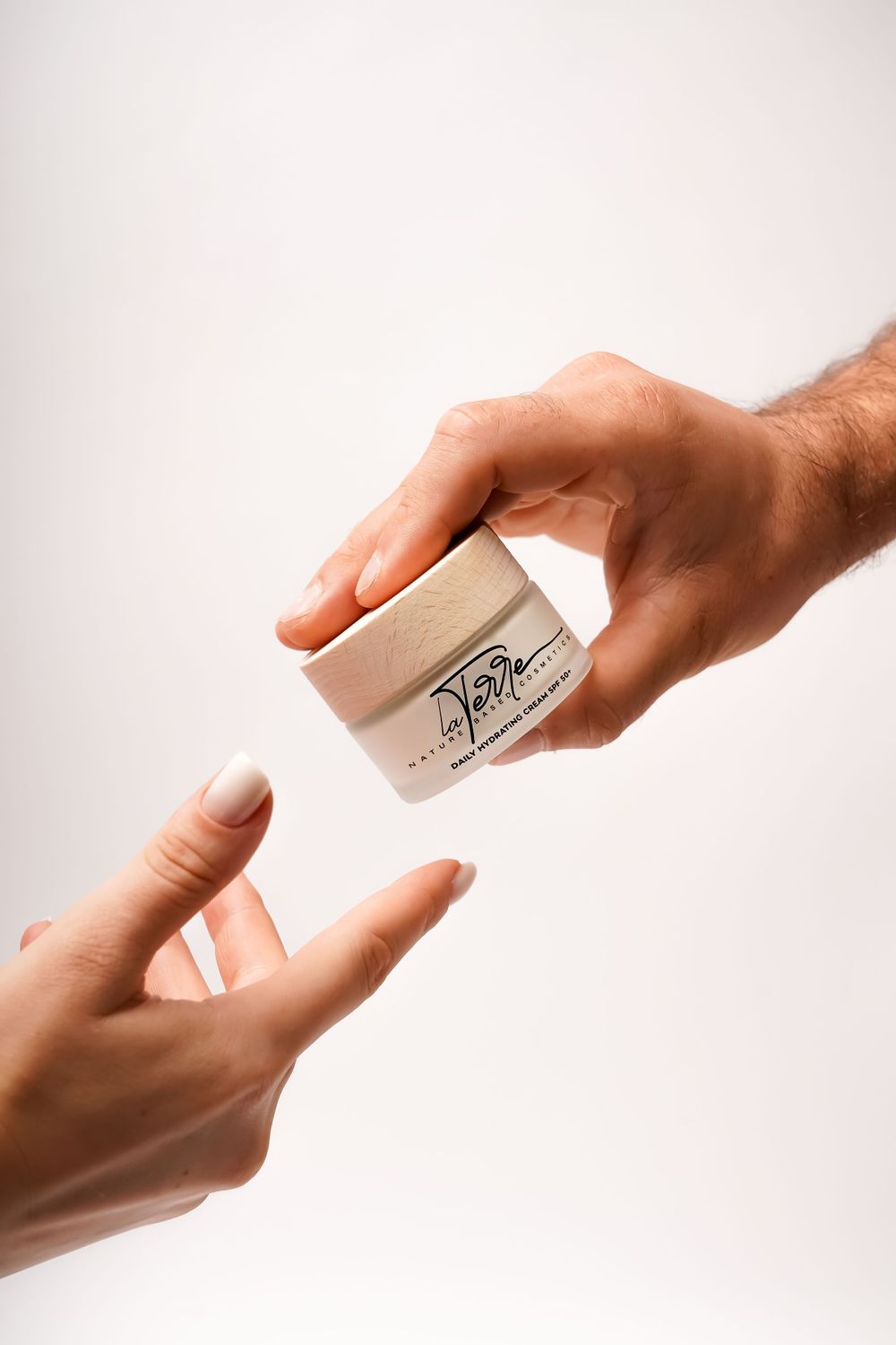 Manos sosteniendo un tarro de crema hidratante
